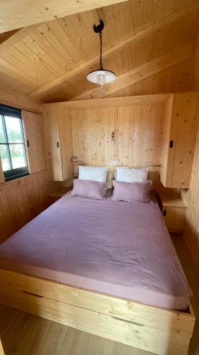 une chambre avec un lit dans une cabane en bois dans l'établissement Lodges dans les vignes Domaine Terre des Mages, à Saint-Geniès-de-Fontedit