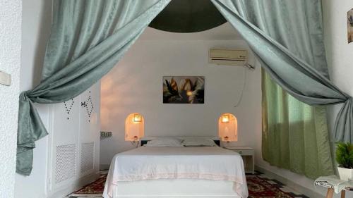 a bedroom with a bed with blue curtains at Flat Marina Kantaoui in Sousse