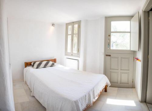a white bedroom with a bed and a window at Kiter's paradise beach house in Pounda