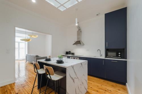 a kitchen with blue cabinets and a kitchen island with chairs at Setubal Terrace apartments in Setúbal