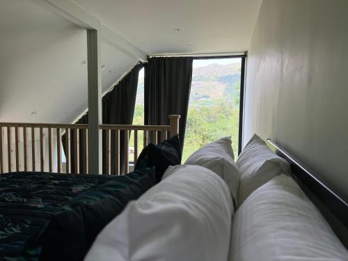 a bedroom with a bed and a large window at Aos Sí - Wellness - Jacuzzi - Lodges in Ballachulish