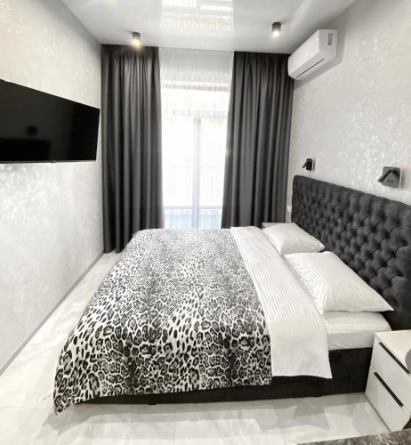 a bedroom with a black and white bed and a television at VEM Apartment Калипсо in Odesa