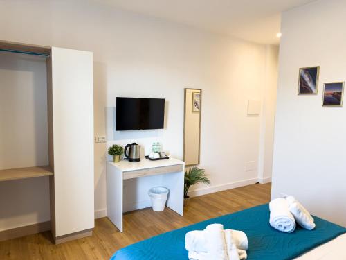 a room with a bed and a desk with a tv at ISOLA 163 Guest House in Fiumicino