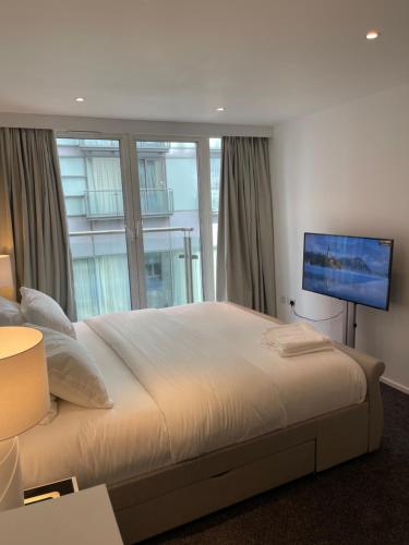 a bedroom with a large bed and a flat screen tv at Modern Luxury 2 bedroom apartment in London Excel in London