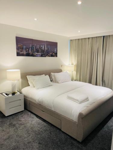 a bedroom with a large white bed with two lamps at Modern Luxury 2 bedroom apartment in London Excel in London