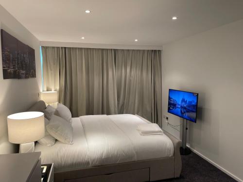 a white bedroom with a bed and a television at Modern Luxury 2 bedroom apartment in London Excel in London
