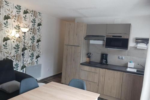 Cette petite chambre comprend une cuisine et une table avec des chaises. dans l'établissement Appartement 4 personnes aux Bottières Résidence le Bochate sur le domaine des Sybelles en Savoie, à Saint-Pancrace