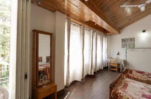 a bedroom with white walls and wooden ceilings and a mirror at Dale Villa in Borpāni