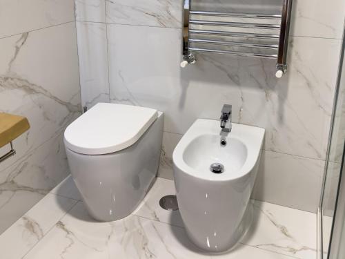 a white bathroom with a toilet and a sink at ISOLA 163 Guest House in Fiumicino