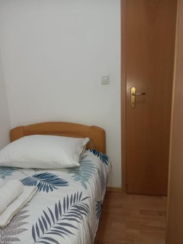 a bedroom with a bed with a blue and white comforter at Apartmani, prenoćište Ana in Tomislavgrad