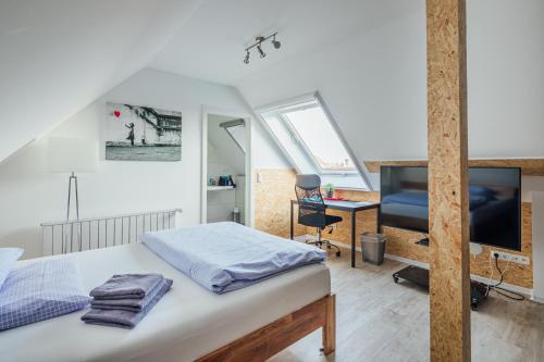 a bedroom with a bed and a tv and a desk at SmartStay Hotel Pumpengasse in Wolfsburg
