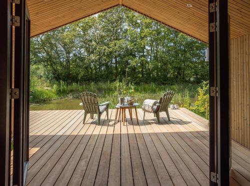 a patio with two chairs and a table on a deck at NEW Hello Zeeland - Watervliet Oyster Lodge in Wissenkerke