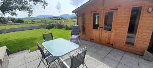 a table and chairs on a patio in front of a cabin at Oaktree Manor in Castlewellan
