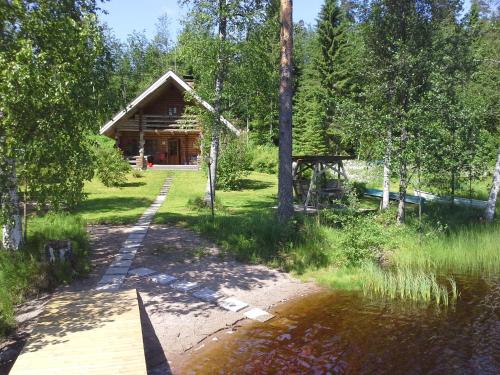 a cabin in the woods next to a body of water at Menninkäinen Cottage in Rutalahti