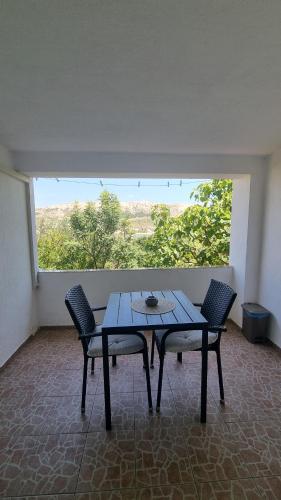 a table and chairs in a room with a large window at Apartments Šešo in Pag