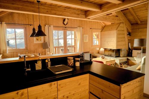 - une cuisine avec un comptoir noir et des murs en bois dans l'établissement Blanc Marine, à Villard-Reculas