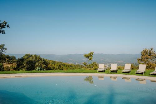 two chairs and a swimming pool with mountains in the background at Podere di Moiata in Campestri