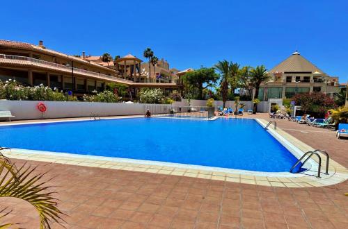 Una gran piscina azul en un complejo turístico. en Apartamento Torres del Sol en Playa Las Vistas - Los Cristianos, en Arona