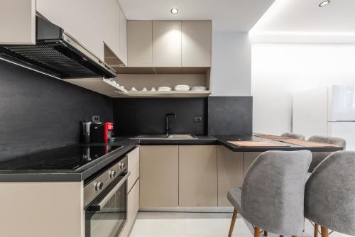 a kitchen with black counter tops and gray chairs at SR Apartments Golem in Golem
