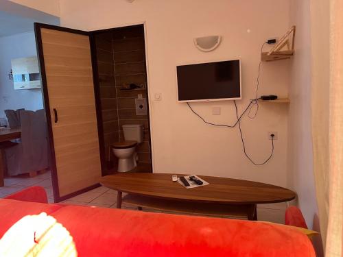 a living room with a table and a tv on the wall at Rêves de vie le "figuerolles" avec terrasse et parking privés in Cassis