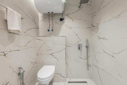 a white bathroom with a toilet and marble walls at SR Apartments Golem in Golem