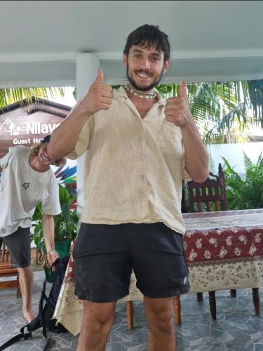 a man giving the thumbs up while standing at Nilaveli Guest House in Nilaveli