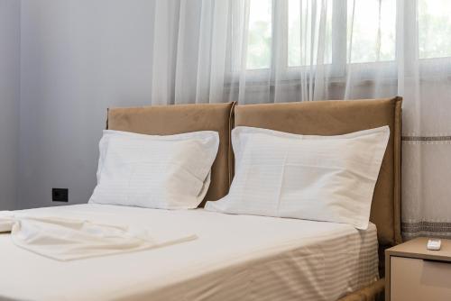a bed with white sheets and pillows in front of a window at SR Apartments Golem in Golem