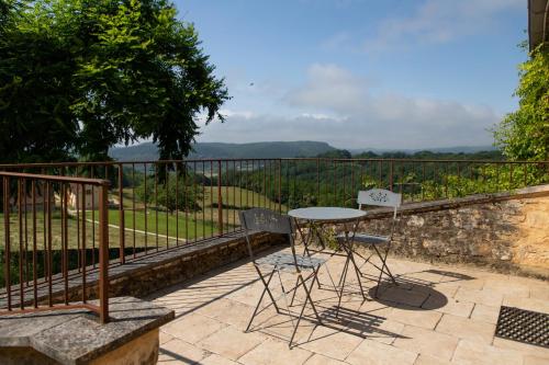 une table et deux chaises assises sur une terrasse dans l'établissement Charmant gîte Linol avec piscine, à Beynac-et-Cazenac