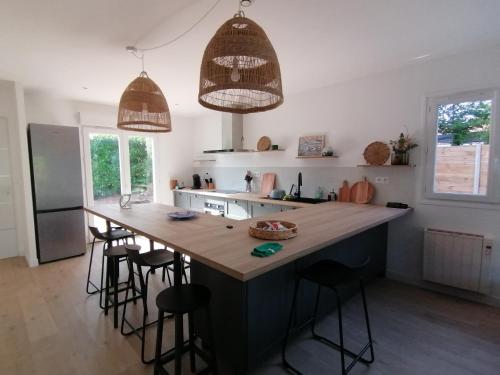 eine Küche mit einer großen Insel mit Barhockern in der Unterkunft Oïhana Villa & Suites - Piscine chauffée - 4km de la plage in Labenne