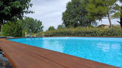une grande piscine bleue avec une terrasse en bois dans l'établissement Maison de plein pied avec vue sur le Lubéron, à Maubec