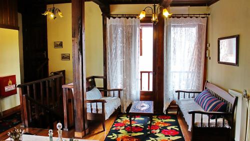 a living room with chairs and a couch and windows at Varosi Guesthouse in Edessa