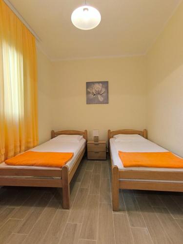 two beds in a room with orange curtains at Apartment Marea in Tivat