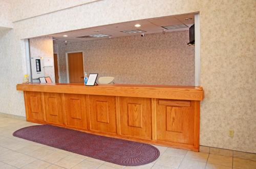 a large wooden counter in a room with a mirror at Budget Host Inn in Allegan