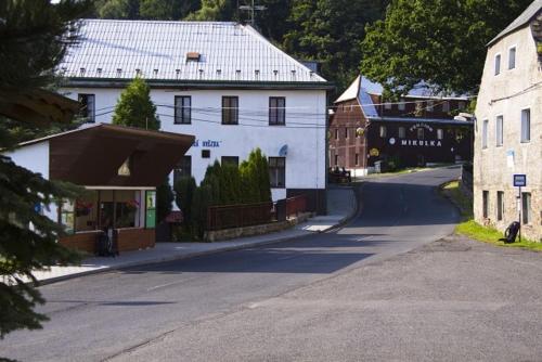 an empty street with a white house and a building at Pension Mikulka in Mikulov v Krušných Horách