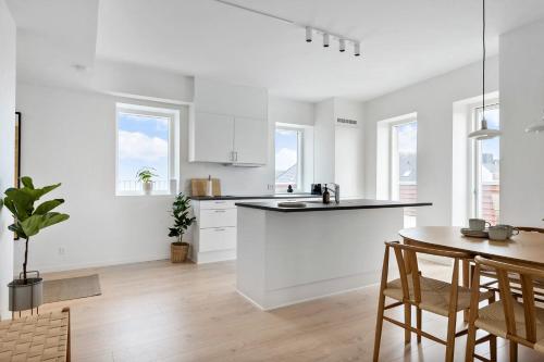 a kitchen with white cabinets and a table and chairs at Penthouse in City Center w Private Rooftop Terrace in Aarhus