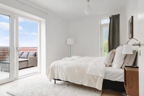 a white bedroom with a bed and a large window at Penthouse in City Center w Private Rooftop Terrace in Aarhus