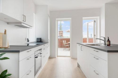 a kitchen with white cabinets and a view of a building at Penthouse in City Center w Private Rooftop Terrace in Aarhus