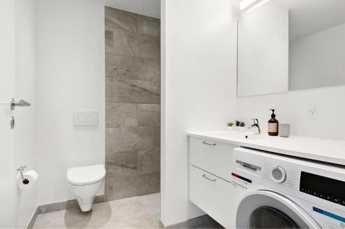 a white bathroom with a toilet and a washing machine at Penthouse in City Center w Private Rooftop Terrace in Aarhus