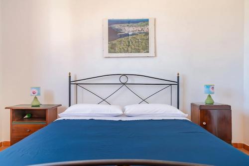 ファヴィニャーナにあるCasa vacanze Villa Raffaelaのベッドルーム1室(青いベッド1台、ナイトスタンド2台付)