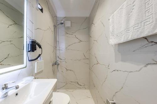 a white bathroom with a sink and a mirror at SR Apartments Golem in Golem