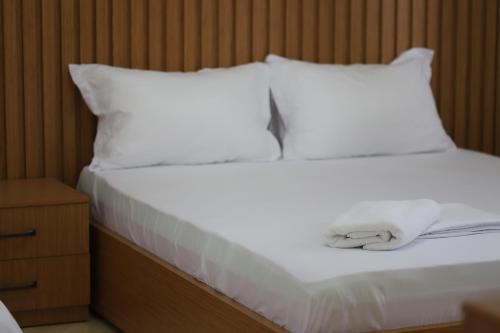 a white bed with white sheets and pillows at Villa Fjorentin Berat in Berat