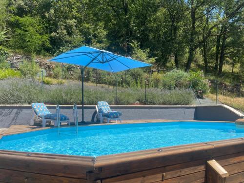 une piscine avec deux chaises et un parasol dans l'établissement Le petit roquet, à Saint-Lazare