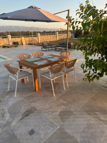 a wooden table with chairs and an umbrella at Cindy Luxury Villas Crete GR in Stavros