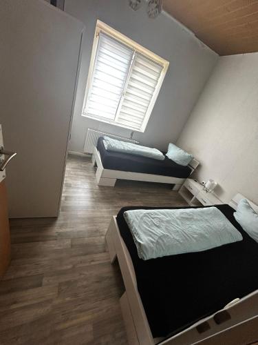 two beds in a room with a window at Ferien- und Monteurunterkunft Alsdorf 2 in Alsdorf