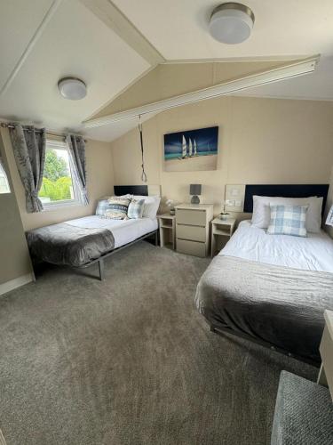a bedroom with two beds and a window at Golden Palm Resort - The Pearl - Coastal Caravan Breaks in Chapel Saint Leonards