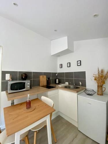 une cuisine avec des armoires blanches et une table en bois dans l'établissement Petit Studio Sablais, à Les Sables-dʼOlonne