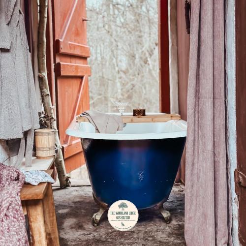 una vasca da bagno blu in una stanza con una finestra di The Woodland Lodge Gisselfeld a Haslev