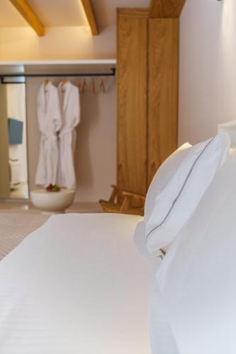 a bedroom with a bed with white sheets and towels at Halo Santorini - Living Experience in Fira