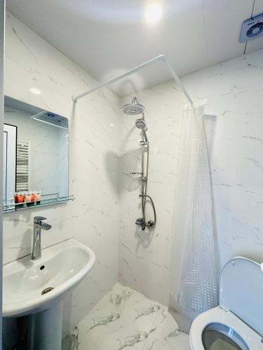 a white bathroom with a sink and a toilet at Woodland Borjomi in Borjomi