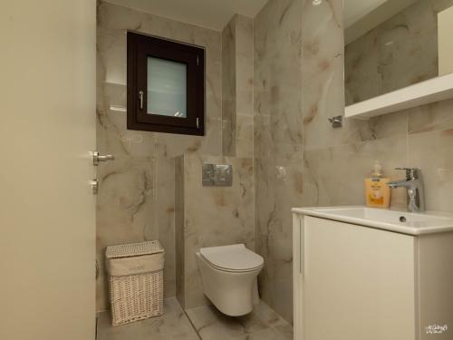 a bathroom with a toilet and a sink and a mirror at Palma Villa & Suite With Pool in Nea Kalikratia